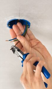 hands of electrician striping the insulation of wires with clippers